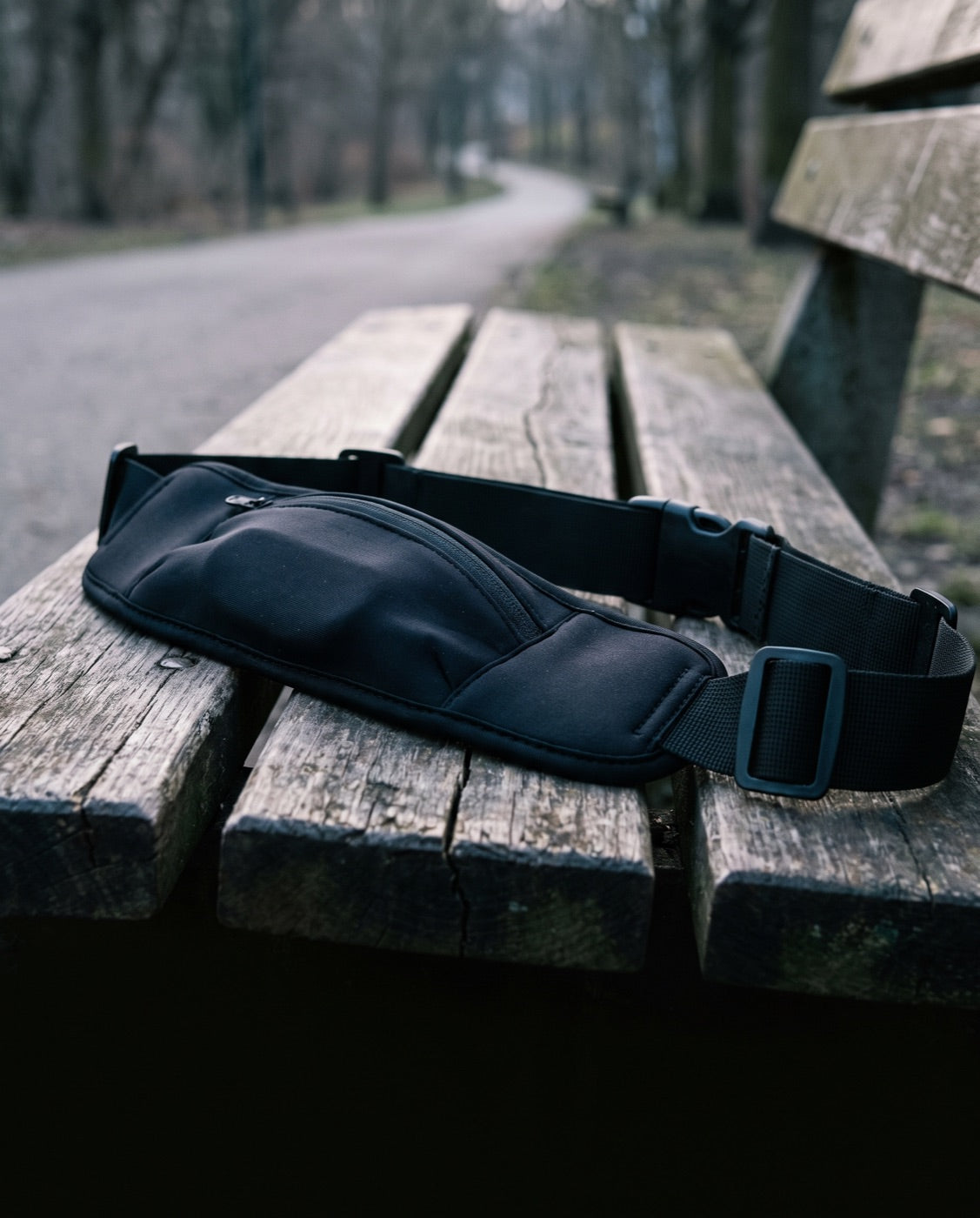 An unused running waist belt with a zip pouch on a park bench