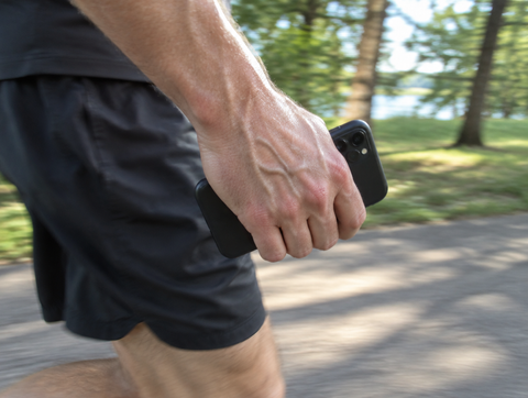 A runner gripping his phone in his hand mid run