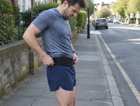 A runner pulling down a running belt that has ridden up
